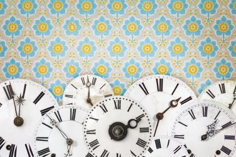 Collection of ancient clock faces in front of retro wallpaper Stock Photos