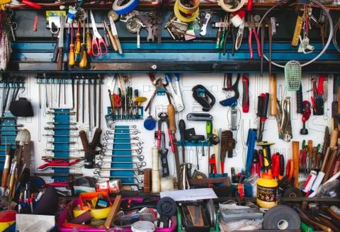 A collection of assorted tools hanging on the wall with a work bench in a gar Stock Photos