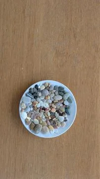 Collection of beach pebbles and shells on a plate Stock-Fotos