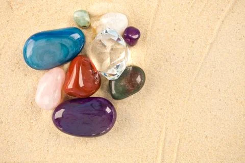A collection of beautiful precious stones laying on sand Stock Photos