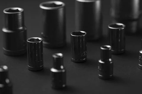 A collection of black chrome socket extensions is arranged on a dark gray Stock Photos