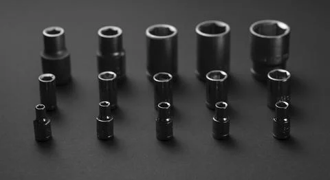A collection of black chrome socket extensions is arranged on a dark gray Stock Photos