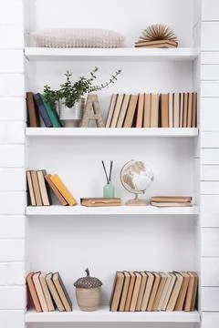 Collection of books and decor elements on shelves indoors Stock Photos