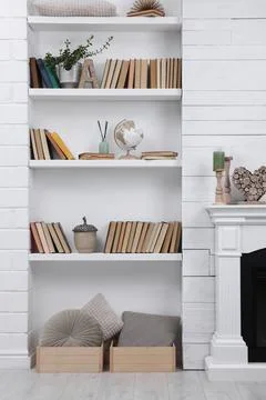 Collection of books and decor elements on shelves indoors. Interior design Stock Photos