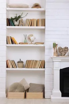 Collection of books and decor elements on shelves indoors. Interior design Stock Photos