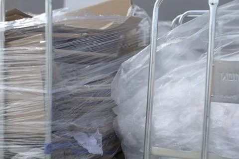 A collection of boxes is securely wrapped in plastic and placed on a cart Stock Photos