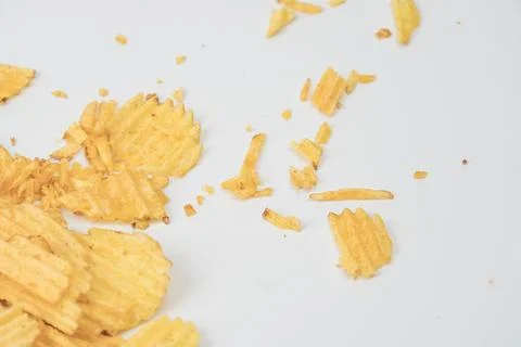 A collection of broken, fried potato chips on a speckled gray surface with so Stock Photos