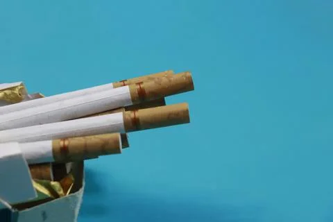 A collection of cigarettes arranged on a blue background Stock Photos