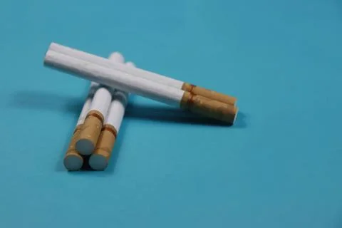 A collection of cigarettes arranged on a blue background Stock Photos