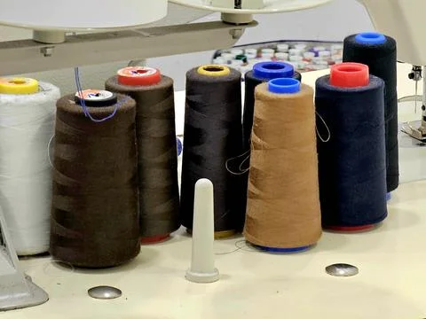 A collection of colorful thread spools, primarily brown, black, and blue Stock-Fotos