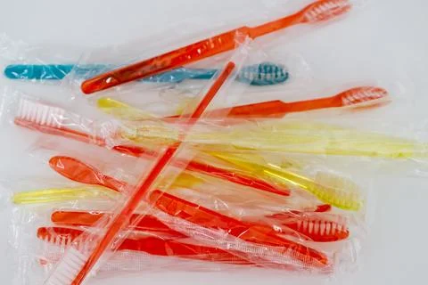 A collection of colorful toothbrushes in plastic packaging, featuring red, .. Stock Photos