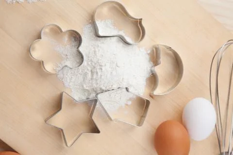 Collection of cookie cutter forms around flour on wooden board Stock Photos