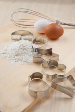Collection of cookie cutter forms around flour on wooden board Stock Photos