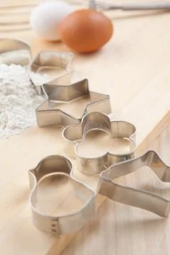 Collection of cookie cutter forms with flour on wooden board Stock Photos