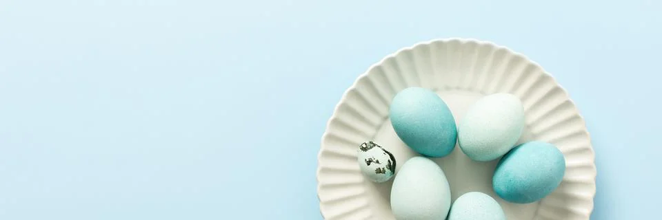 A collection of decorated blue Easter eggs sits on a white plate, showcasing  Stock Photos