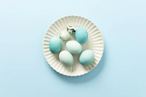 A collection of decorated blue Easter eggs sits on a white plate, showcasin.. Stock Photos
