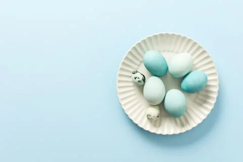 A collection of decorated blue Easter eggs sits on a white plate, showcasing  Stock Photos