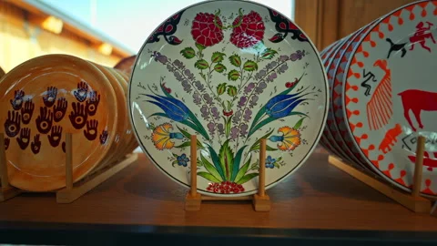 A collection of decorative ceramic plates is displayed on a wooden shelf, s... Stock Footage 339309712