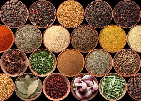 Collection of different aromatic spices and herbs on black background, flat l Stock Photos