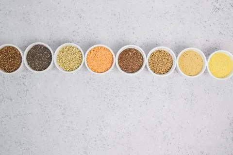 Collection of different groats on grey background. Top view of buckwheat, chia Stock Photos