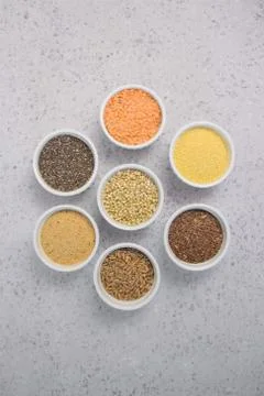 Collection of different groats on grey background. Top view of buckwheat, chia Stock Photos