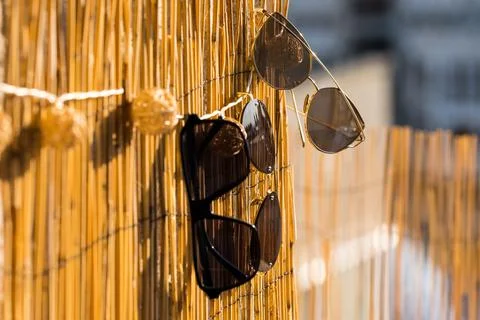 Collection of different sunglasses models reflecting the sun stay on a bamboo Stock Photos