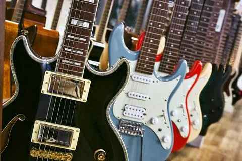 A collection of electric solid body guitars hanging in a row Foto stock