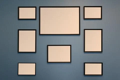 Collection of empty wooden picture frames on a dark blue wall. Stock Photos
