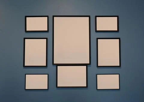 Collection of empty wooden picture frames on a dark blue wall. Stock Photos
