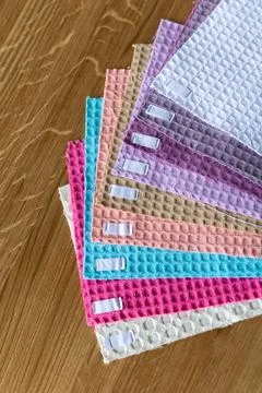 Collection of fabric samples arranged in a stack on a wooden table showing .. Фото