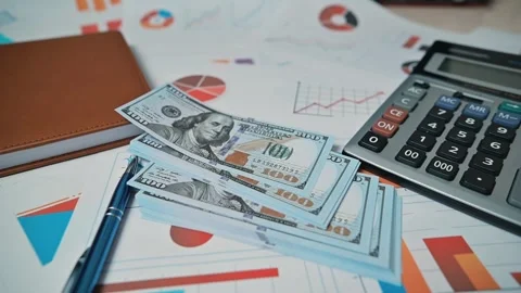A collection of financial documents, charts, and a calculator is arranged on a Stockbeeldmateriaal 338301490