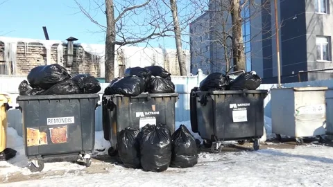 Collection of garbage bags next to dumpsters in winter in a city neighborhood Stock Footage 328438161