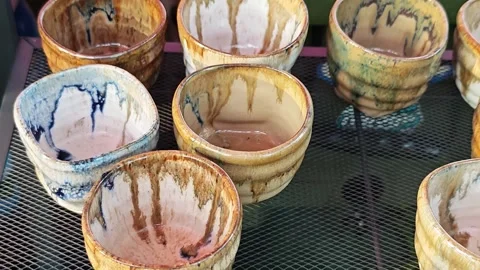 Collection of handmade ceramic cups with unique drip glaze patterns. Видео 339779864