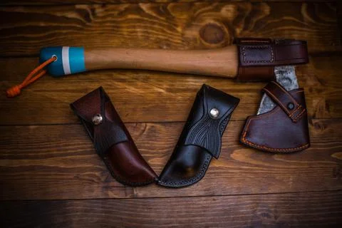 Collection of Leather Knife Sheaths and Hatchet on Rustic Wooden Surface Stock Photos