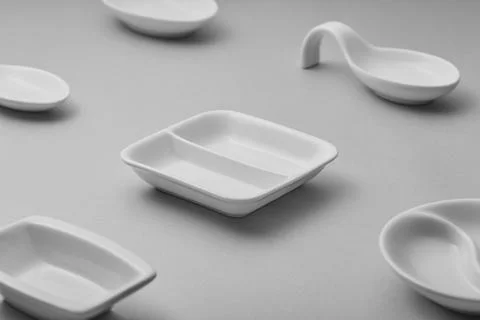 A collection of minimalist white ceramic tableware is arranged on a gray su.. Stock Photos