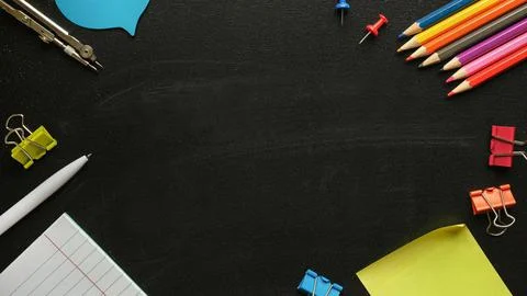 Collection of multi-colored stationery on the background of a black school bo Stock Photos