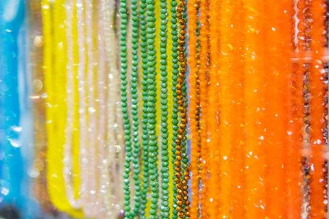 A collection of multi-colored, variably sized gemstone beads cascading on a n Photos