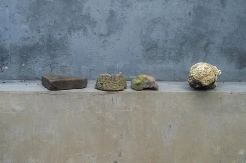 A collection of natural stones and a rectangular brick are displayed in a r.. Stock Photos