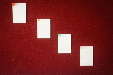 Collection of note papers pinned on a red board ready for filling in quotes. Stock Photos