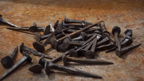 A collection of old handmade iron nails lay on old metal surface. Stock Footage 130113020
