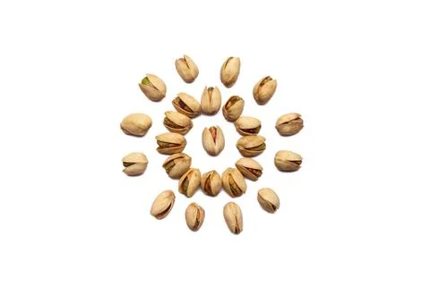 A collection of pistachio nuts lie in the shape of a circle or sun on an isol Foto stock