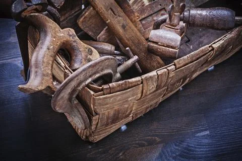 Collection of retro-styled tools in wicker box on wooden board Stock Photos