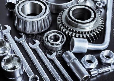 Collection of silver tools and mechanical parts arranged on a dark work surface Stock Photos