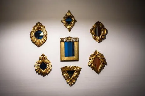 Collection of small mirrors hanging on the wall with golden vintage frames Stock Photos