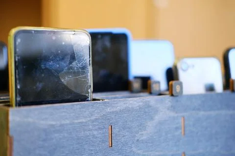 Collection of students cell phones stored in a wooden box, showcasing various Stock Photos