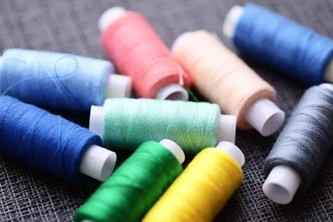 A collection of thread spools arranged neatly on a table, suitable for craft or Stock Photos