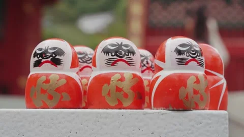 A collection of traditional Daruma dolls displayed in front of a large vibrant Stock Footage 344279799