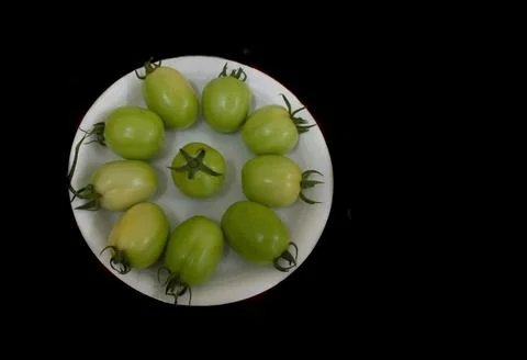 Collection of unripened raw green tomatoes isolated on black Stock Photos