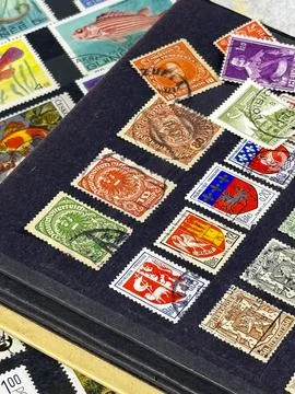 Collection of various postage stamps displayed on a black album Stock Photos