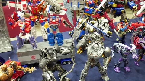 Collectors showcase prized Transformers action figures on tables at a lively Stock Footage 301626241